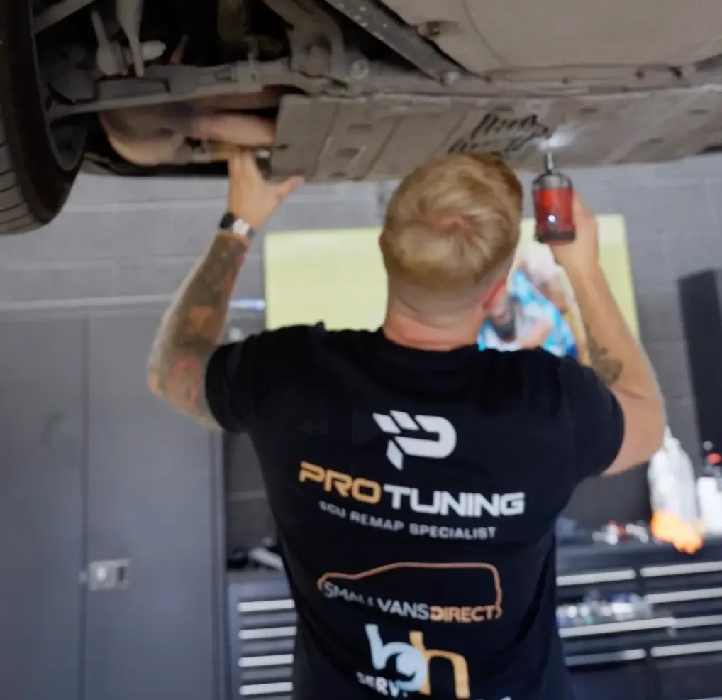 Pro Tuning technician working beneath a car on the workshop ramp
